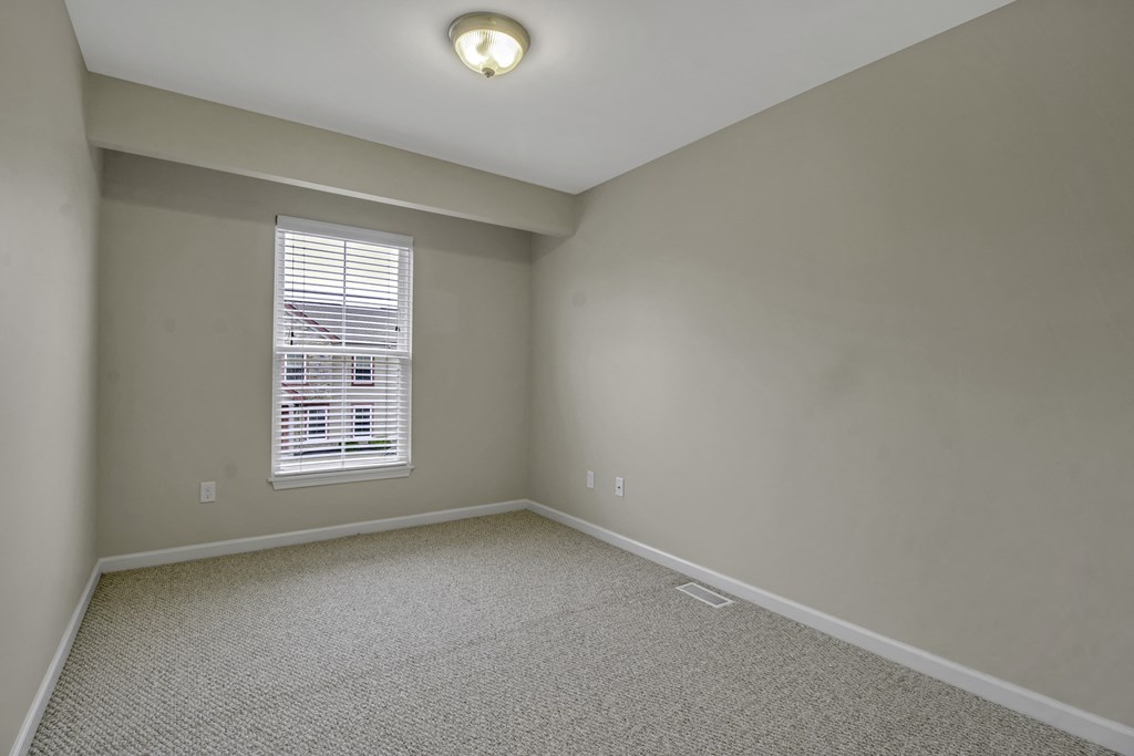 an empty room with white carpet and a window