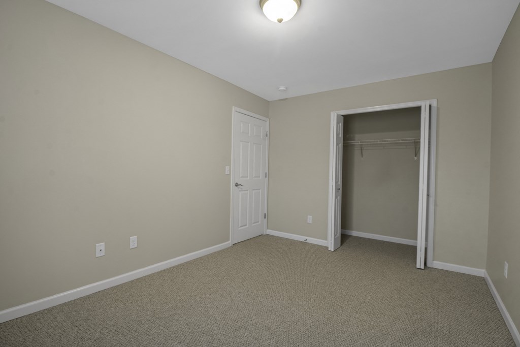 a bedroom with a door to a closet and a carpeted floor