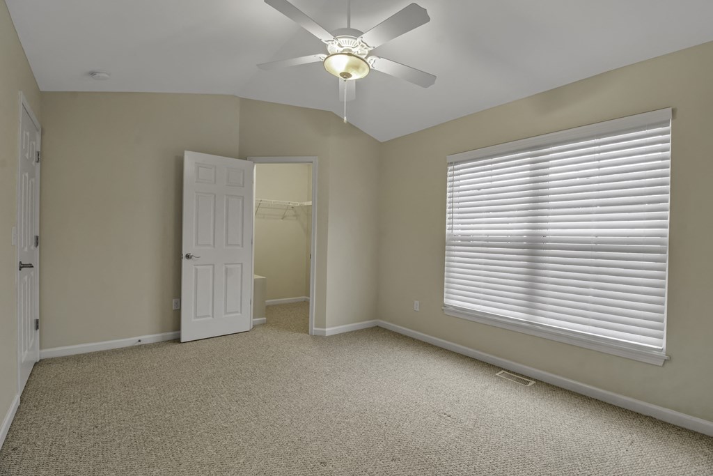 an empty bedroom with a ceiling fan and a window