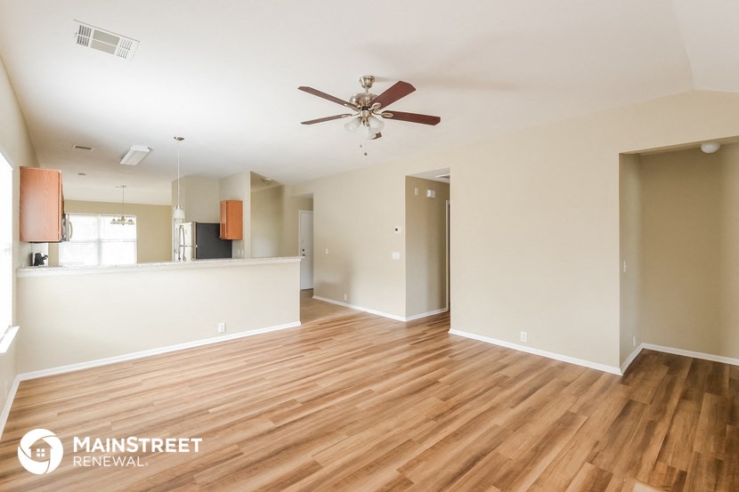 the living room and dining room with wood flooring and a ceiling fan