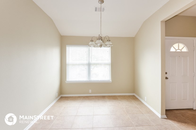 an empty dining room with a white door and a window