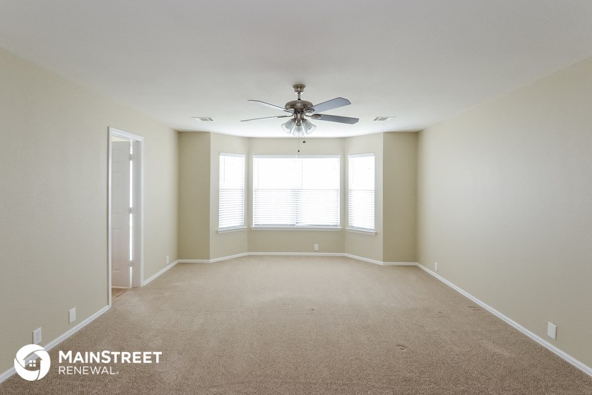 an empty living room with a ceiling fan and a window