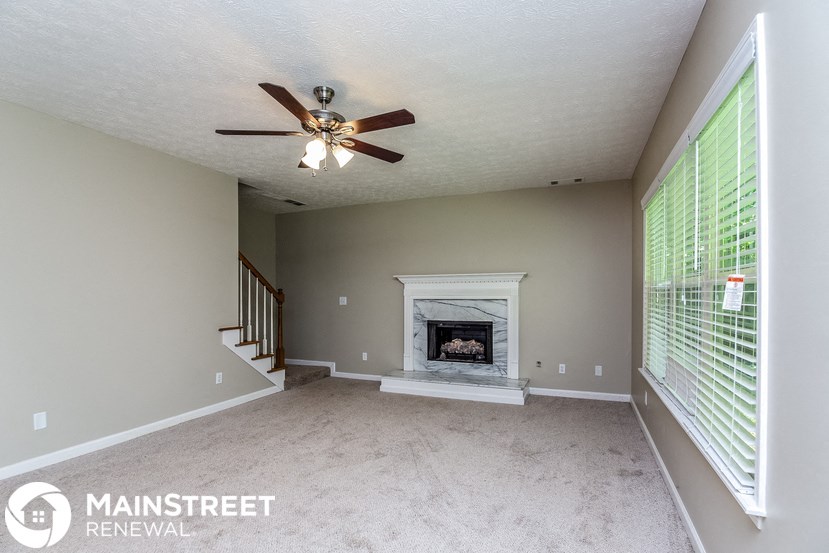 a living room with a fireplace and a ceiling fan
