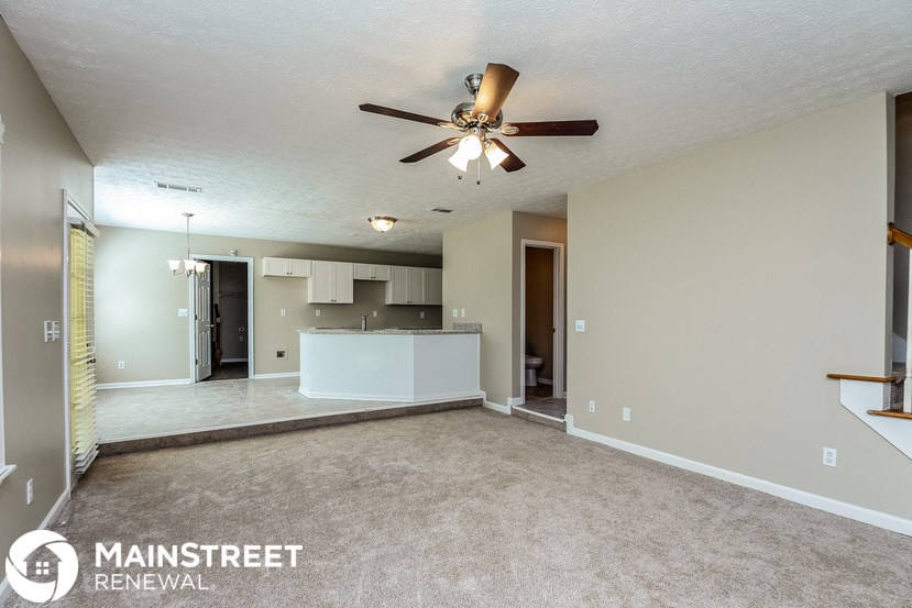 an empty living room and kitchen with a ceiling fan