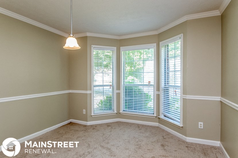 a dining room with three windows and a carpeted floor