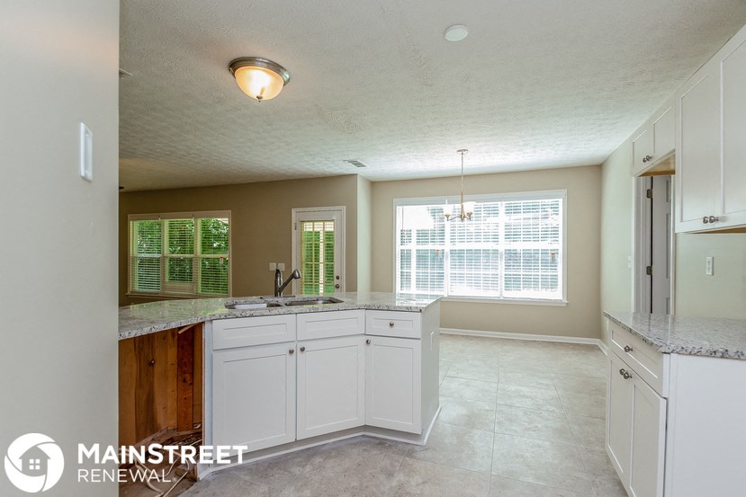 a kitchen with white cabinets and a large window