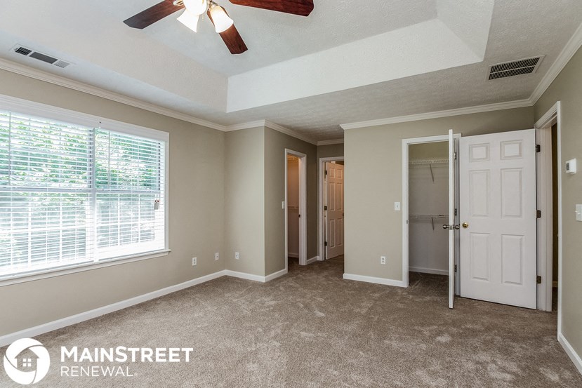 the master bedroom has a large window and carpeted flooring