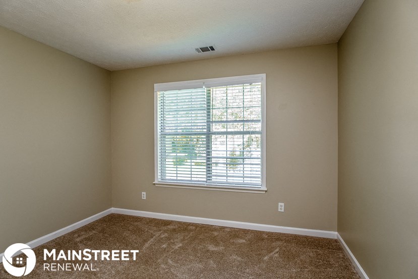the master bedroom has a large window and carpeted flooring