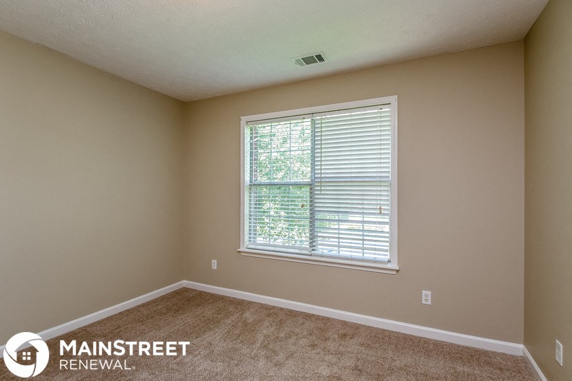 the upstairs bedroom has a large window and carpeted flooring