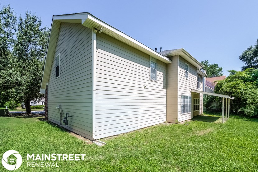 the backyard of a house with a garage and a lawn