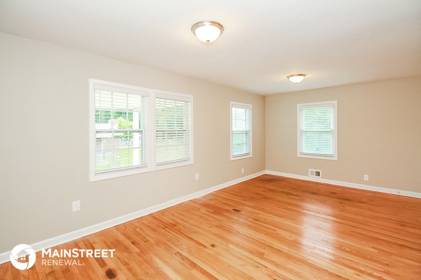 the spacious living room with hardwood flooring and windows