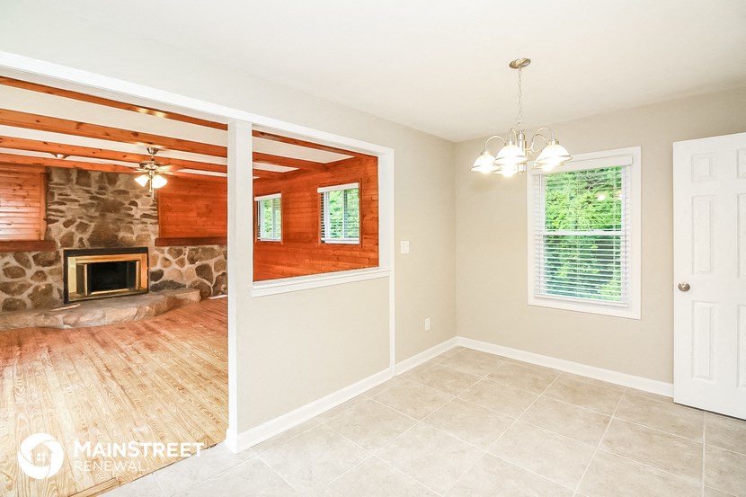 the living room has a stone fireplace and tile flooring