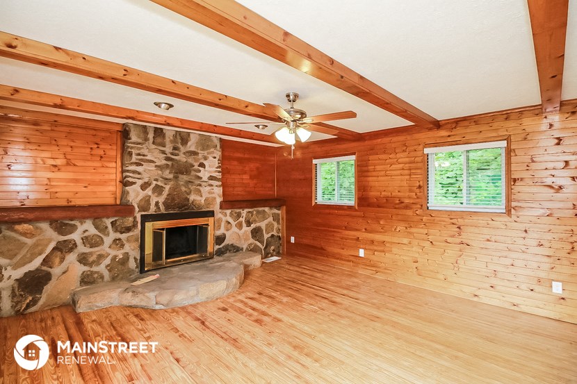 the living room of a cabin with a stone fireplace
