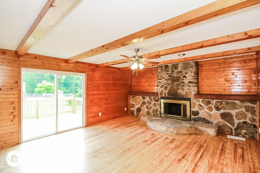 a living room with a stone fireplace and wood floors