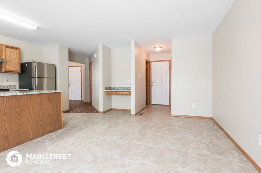 a living room with a kitchen and a door to a hallway