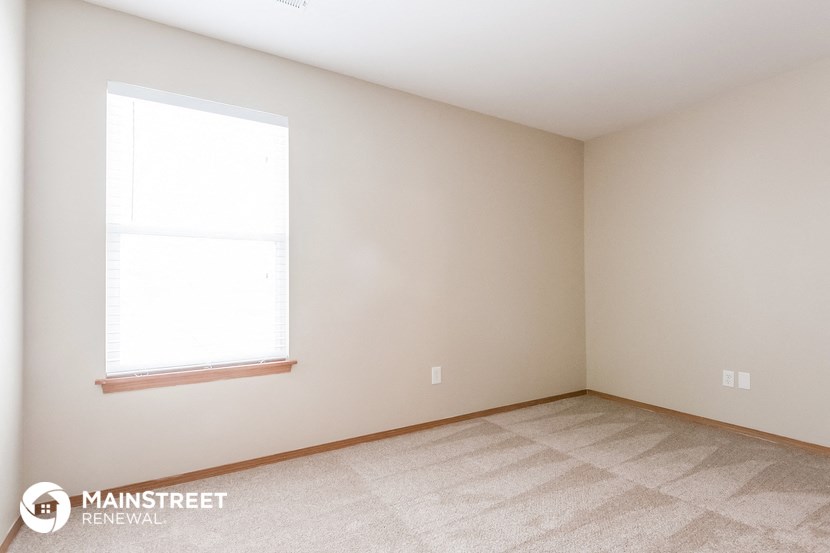 the upstairs bedroom with a large window and beige walls