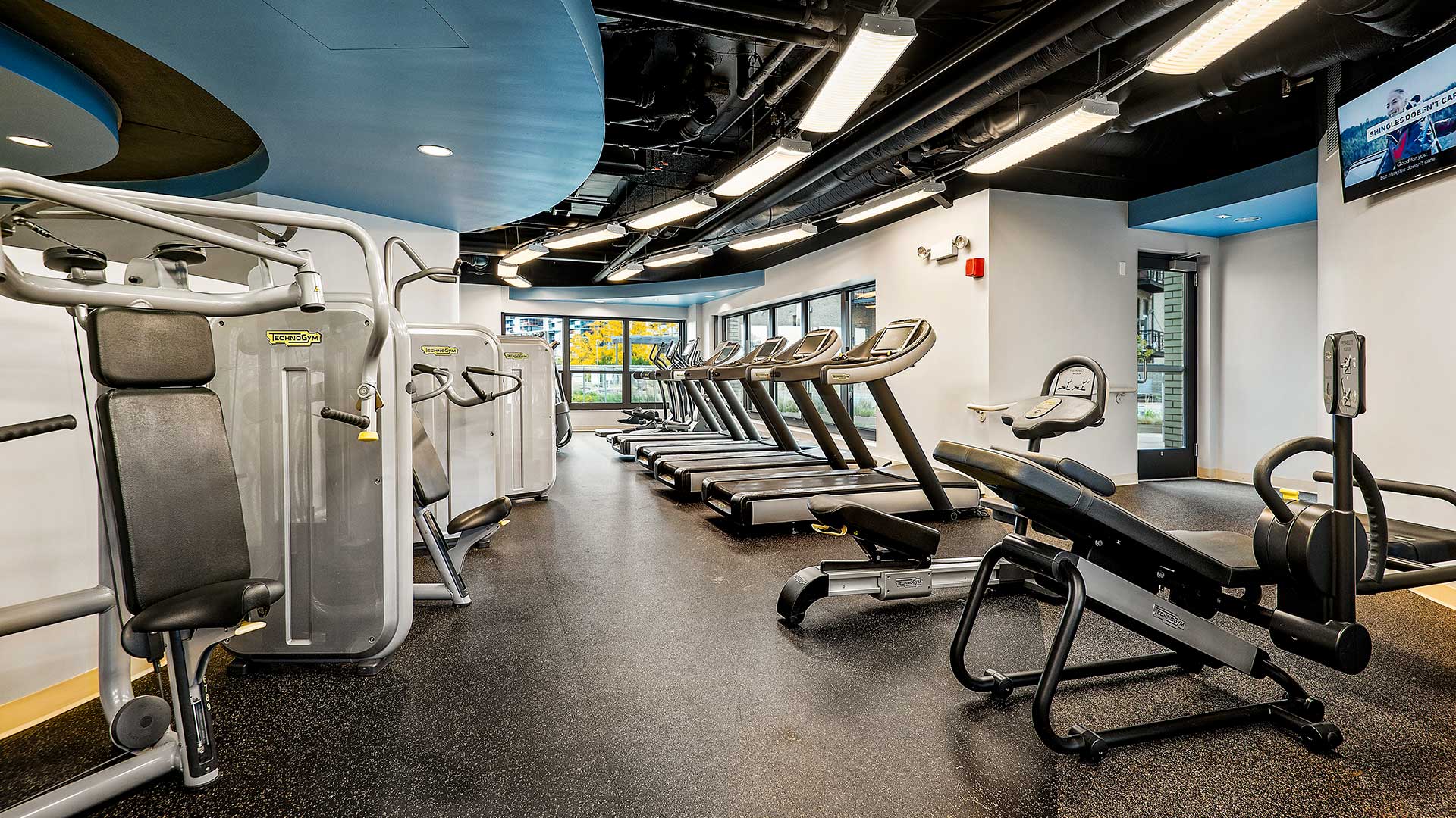Gym equipment line the left side and tread mills the right in the fitness center at Eleven Thirty.
