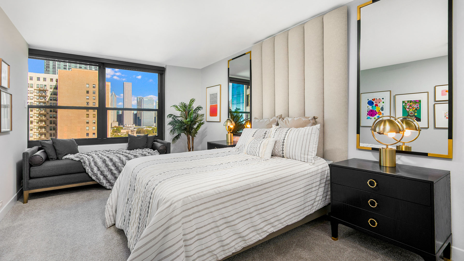 A bedroom at Eleven Thirty. A sofa bench sits beneath the window behind a large, comfortable bed.