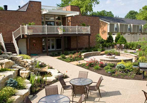 a patio with tables and chairs in front of a brick building