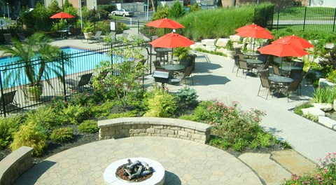 a patio with tables and umbrellas near a swimming pool