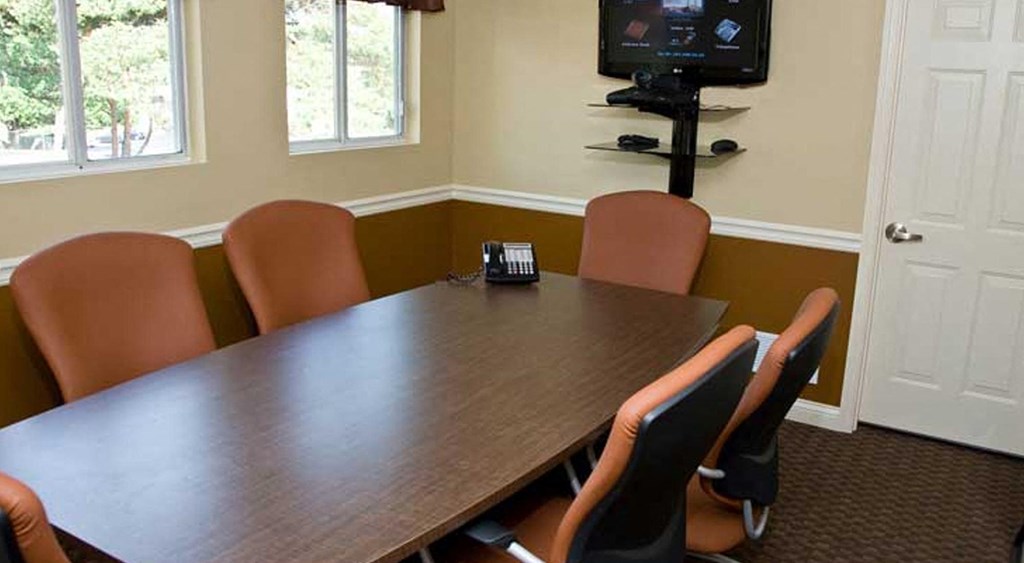 a conference room with a table and chairs and a television