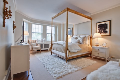 A bedroom with a four poster bed and a white rug.