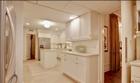 A kitchen with white cabinets and a refrigerator.