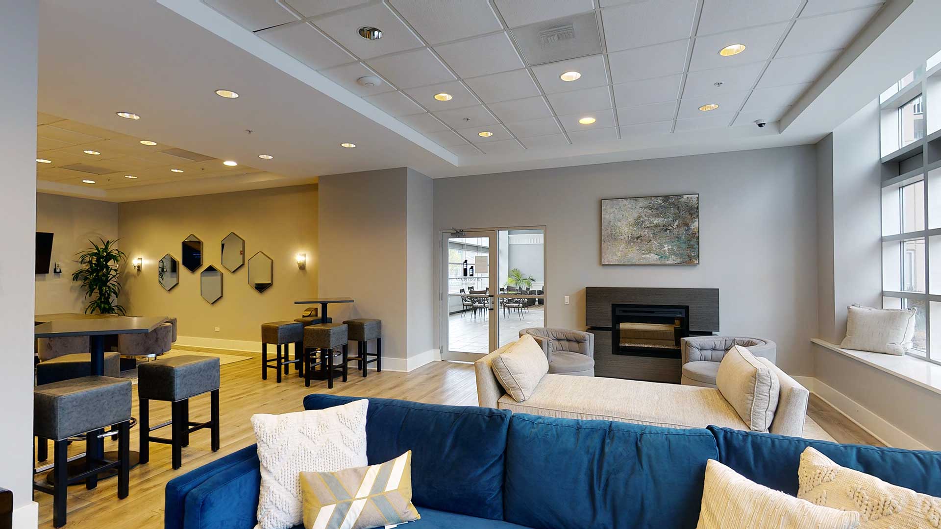 Looking across the Party Room at Grand Plaza. Couches and lounge chairs are on the right. The bar and high top tables are on the left.