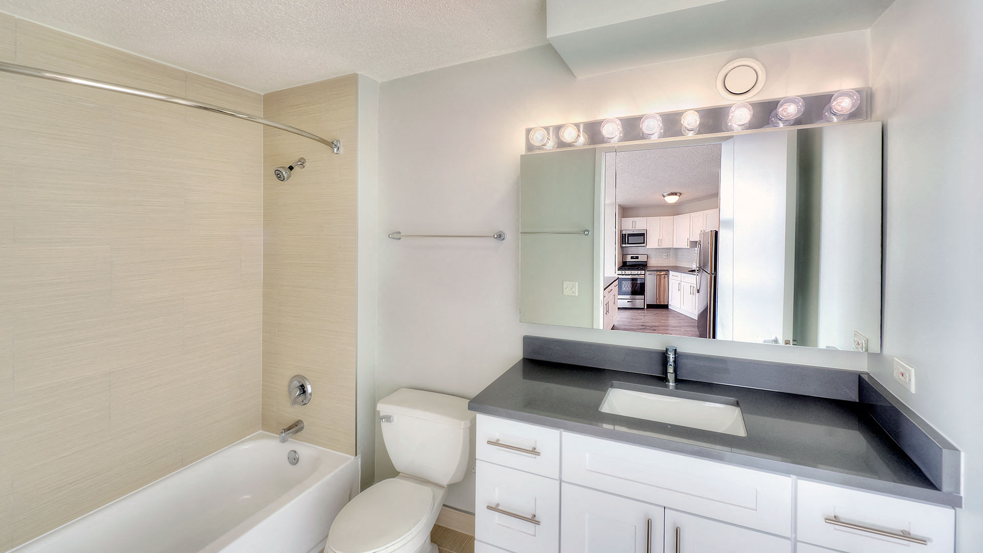 A bathroom with the vanity and mirror on the right and the shower, tub and toilet on the left.