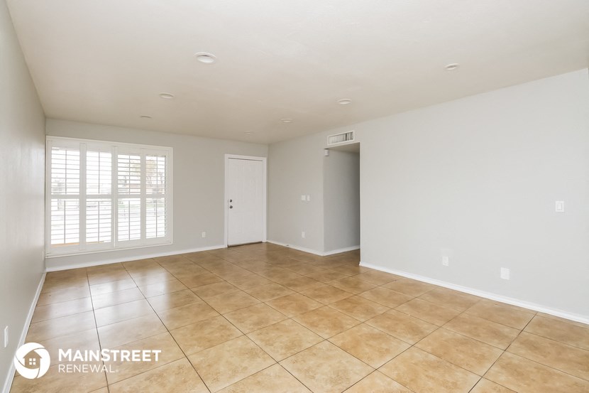 the spacious living room with tile flooring and white walls