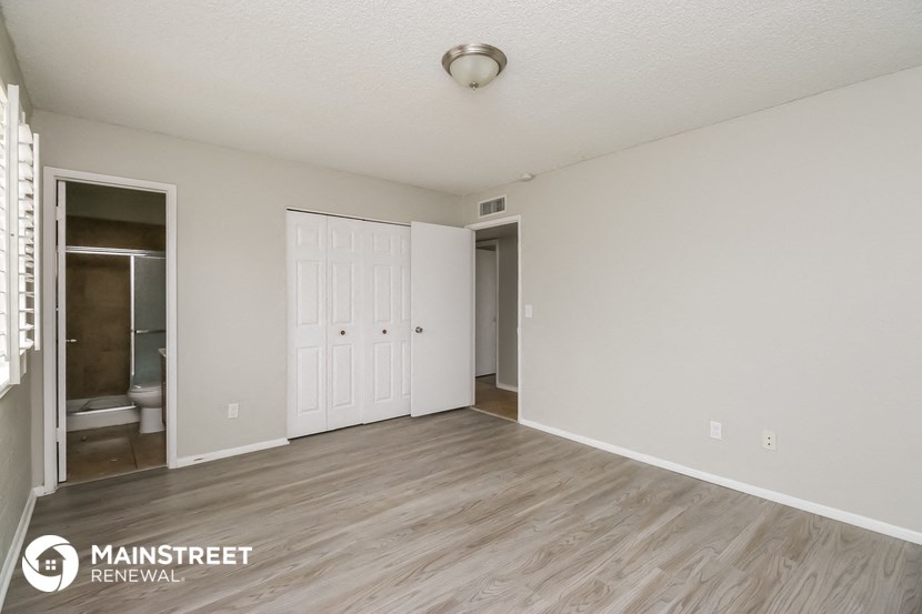 the spacious living room with white walls and wood flooring