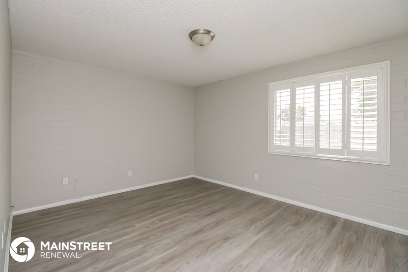the spacious living room with wood floors and white walls