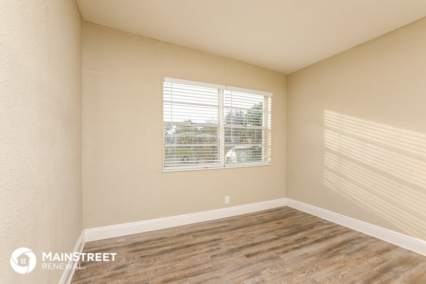 the spacious living room with a large window and wood flooring