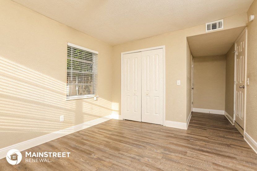 the living room of an apartment with wood floors and a white door