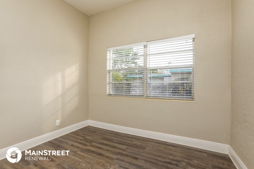 the living room of an apartment with wood floors and a window