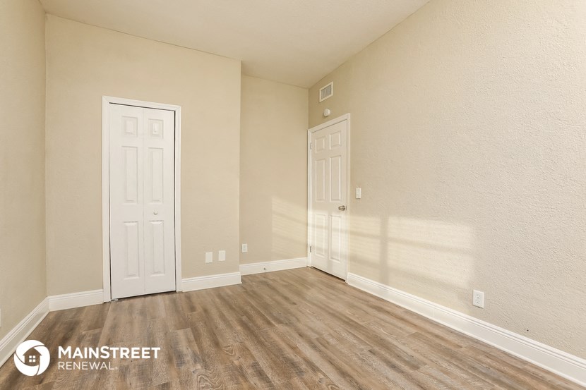the upstairs bedroom of an apartment with wood flooring and two doors