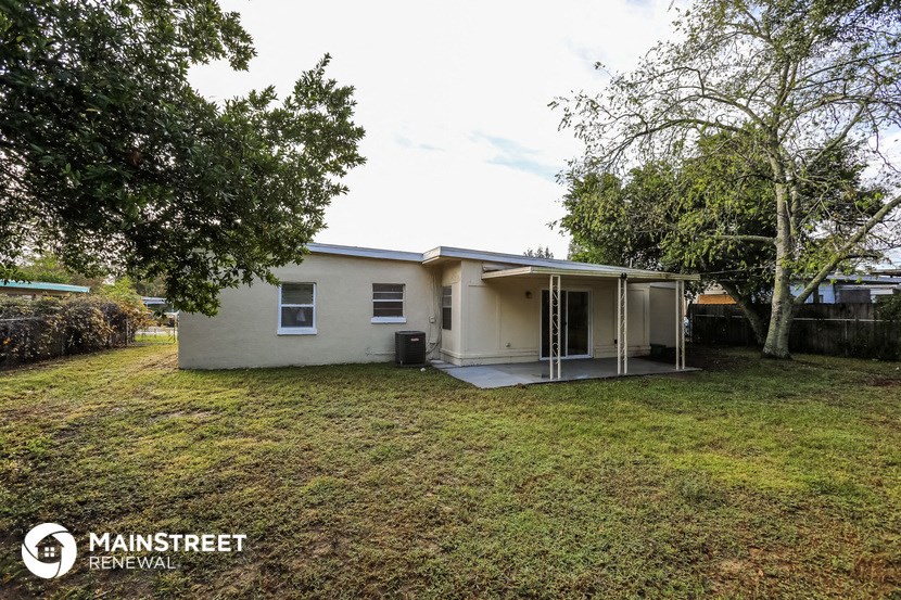 a small white house with a yard and trees