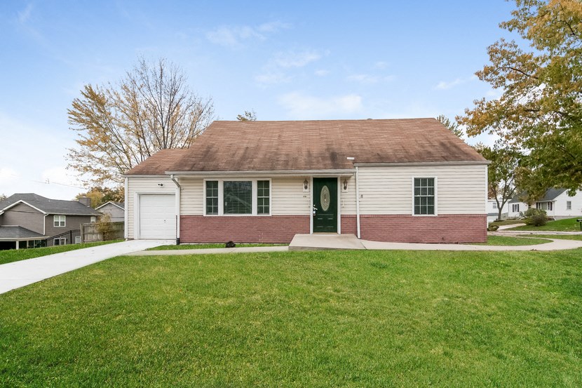 the front of a white house with a green door and a lawn