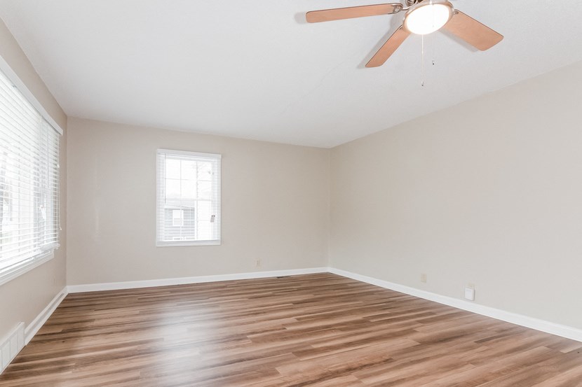 an empty living room with wood floors and a ceiling fan