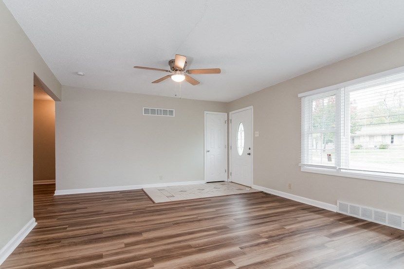 an empty living room with wooden floors and a ceiling fan