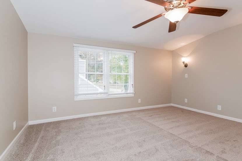 an empty living room with a ceiling fan and a window
