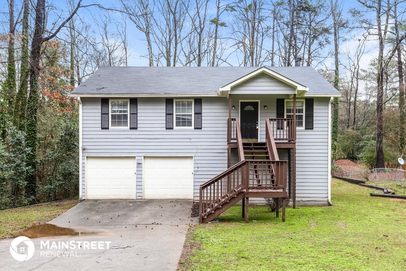 the front of a white house with a deck and a garage