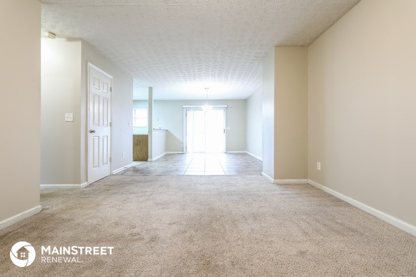 an empty living room with carpet and a white door