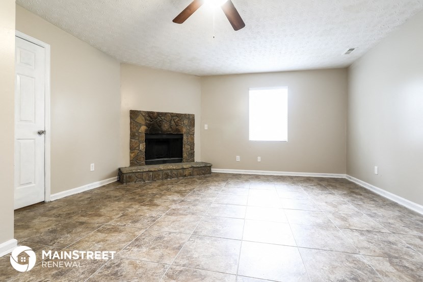 an empty living room with a fireplace and tile floors