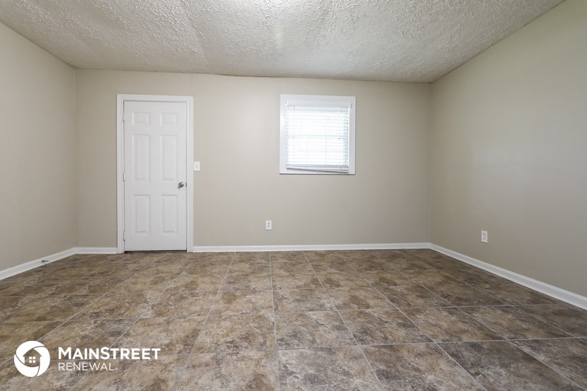 the living room of a home with a tile floor and a white door
