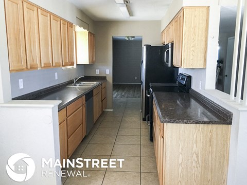 a kitchen with black counter tops and wooden cabinets and a black refrigerator