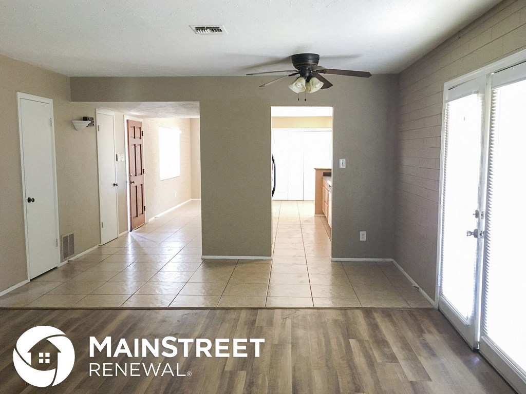 an empty living room with tile flooring and a ceiling fan