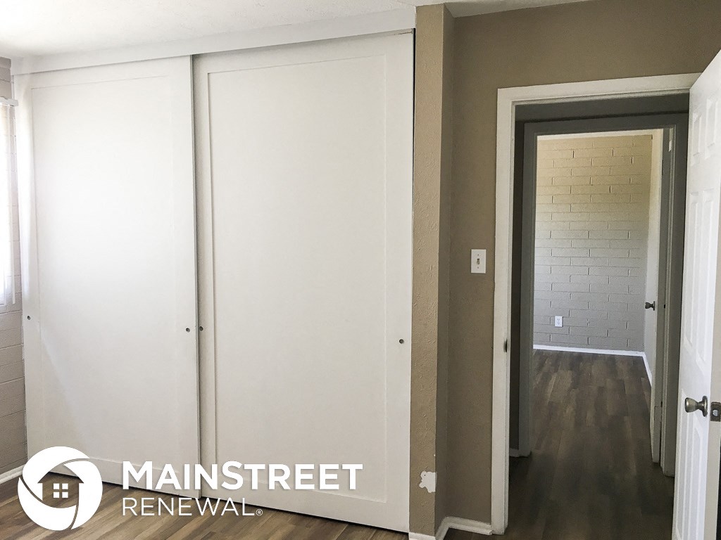 a hallway with white doors and a wood floor and a white wall with a doorway