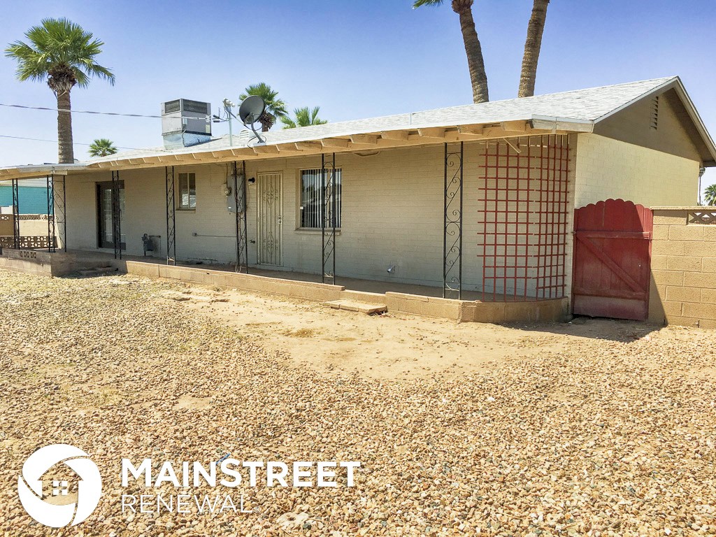 a small house with a yard and palm trees