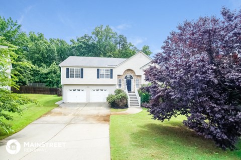 a white house with a driveway and a purple tree